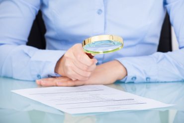 Businesswoman Looking At Document Through Magnifying Glass